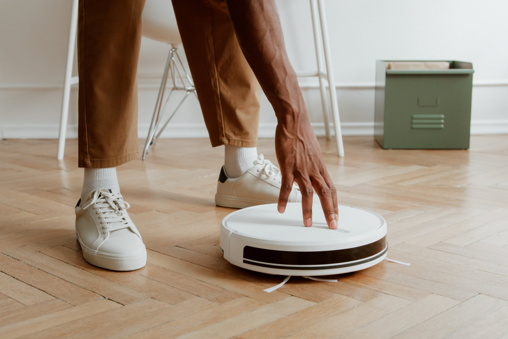 black man pressing a robotic vacuum cleaner button