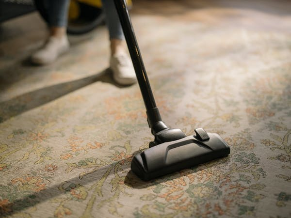 person vacuuming carpeted floor